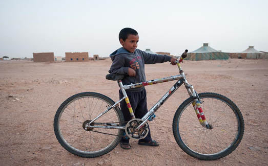 Un niño se apoya en su bicicleta en uno de los campos de refugiados